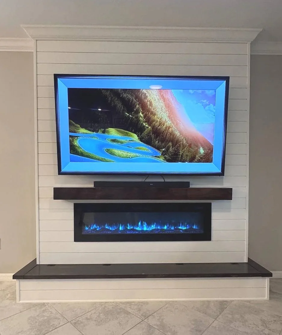 Completed white shiplap fireplace media wall in Houston Texas with mounted TV, electric fireplace, dark wood mantel, and matching lower bench.