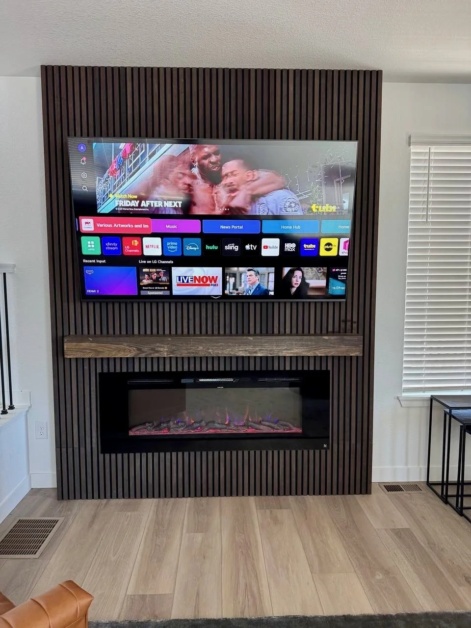 custom slat fireplace TV wall with wood mantel and modern electric fireplace