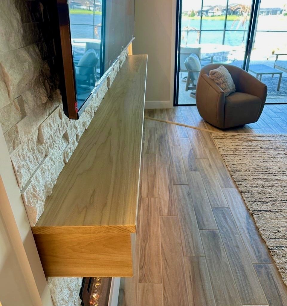 Close-up of custom wood mantel over stone media wall with large TV and fireplace