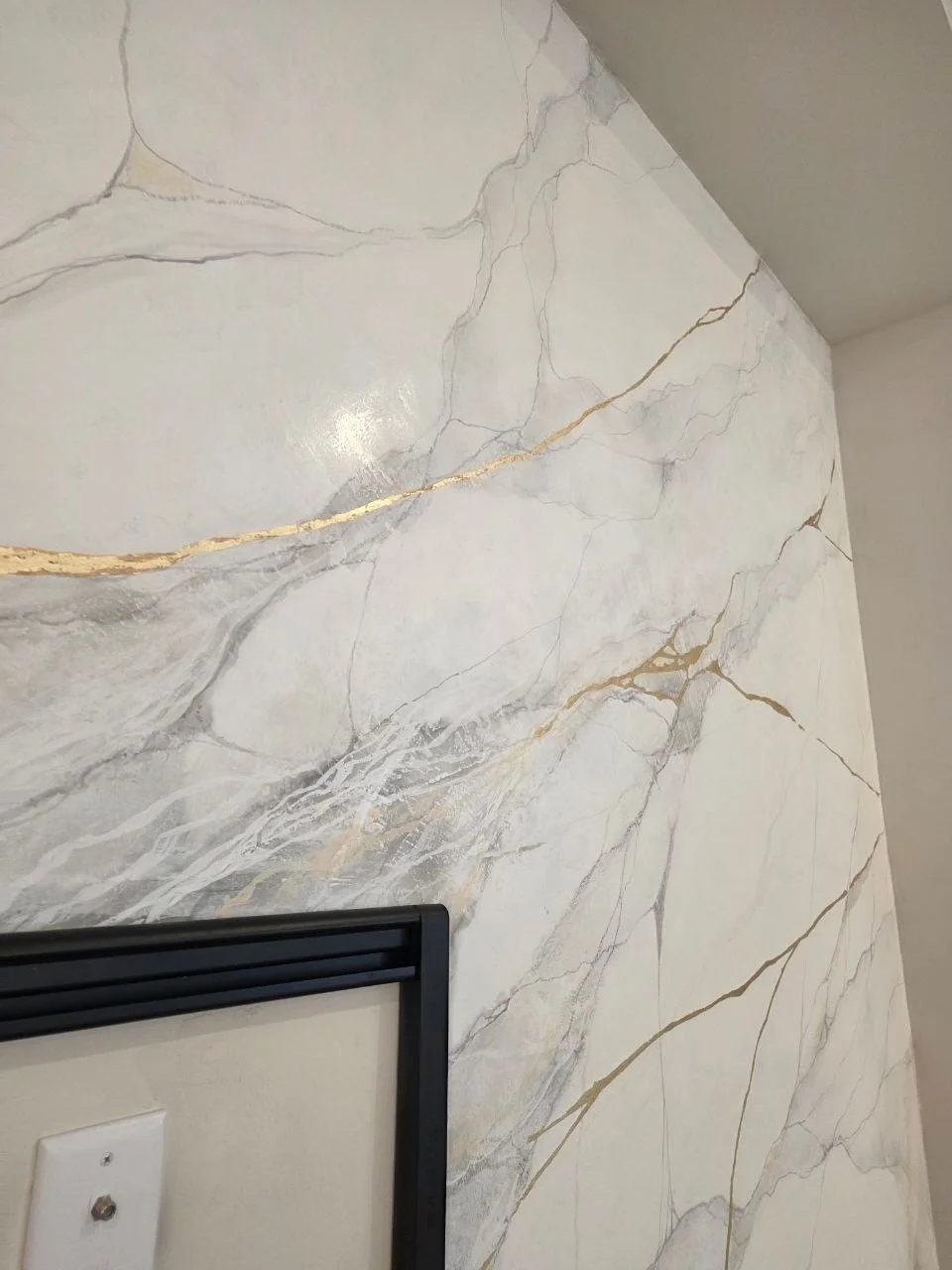 Corner view of luxury Venetian plaster feature wall showing handcrafted marble-inspired movement and decorative metallic veining.