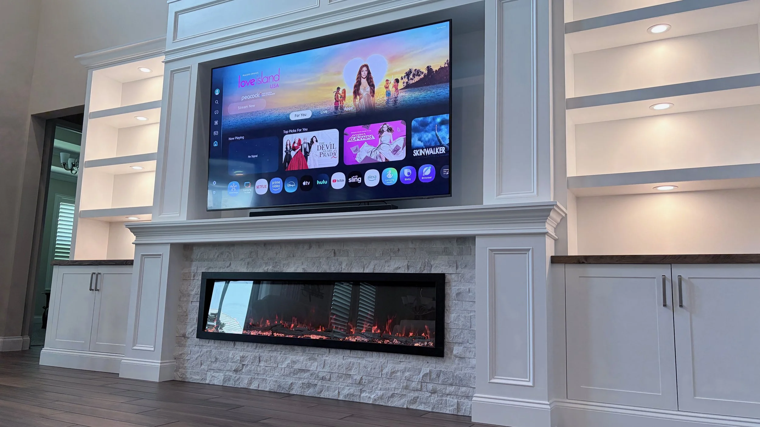 Traditional fireplace media wall with decorative trim, stone surround, custom cabinetry and built-in shelving