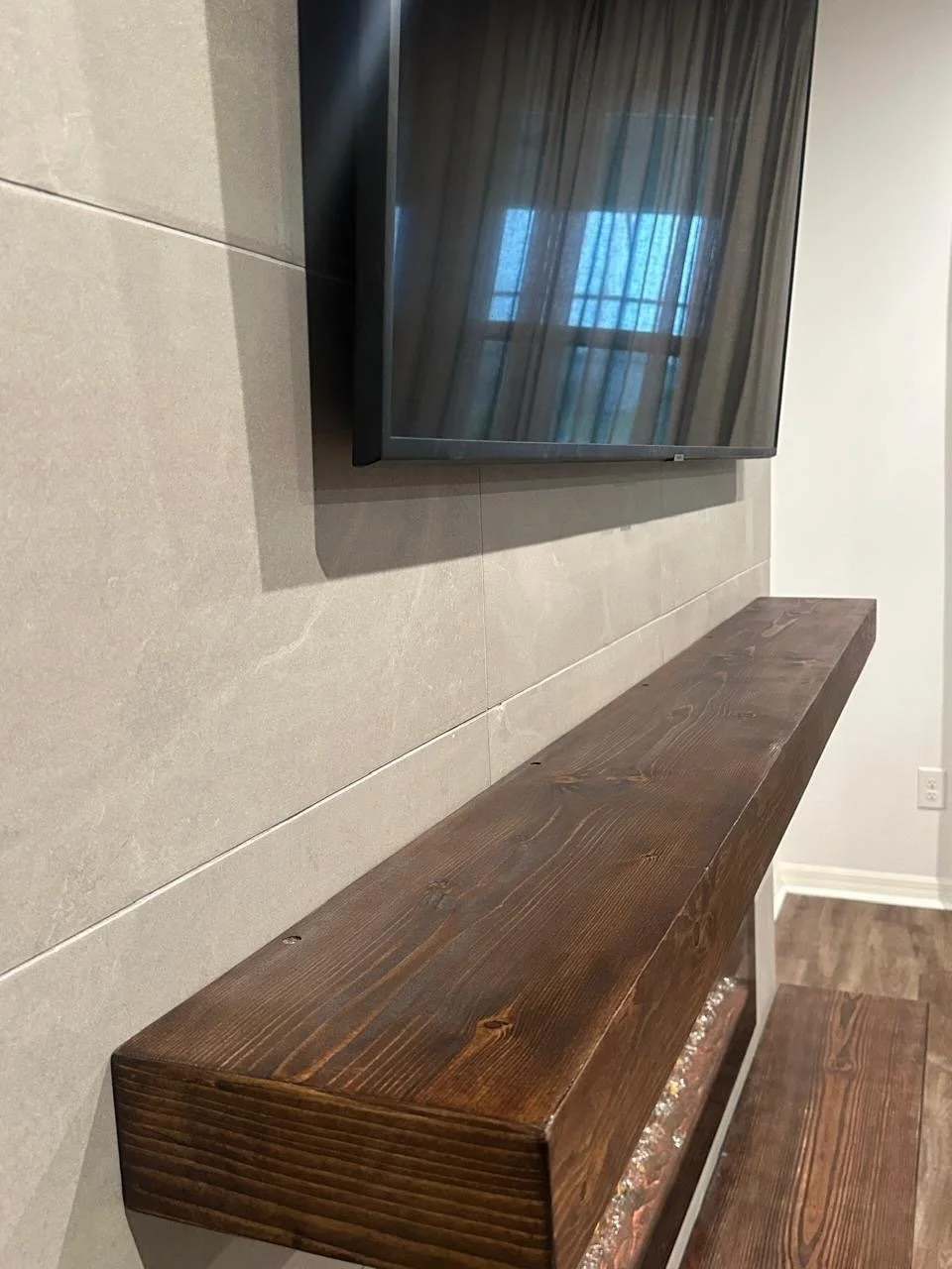 floating wood mantel installed on porcelain tile wall