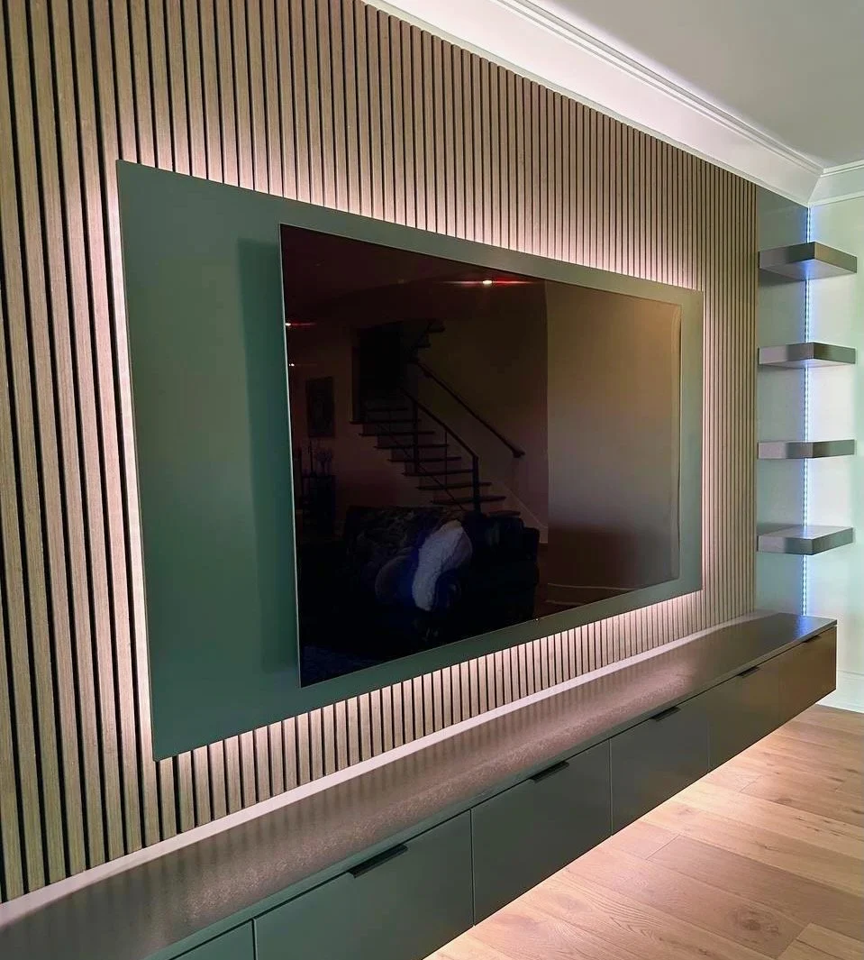 Close view of floating TV panel with LED backlighting, wood slat wall and custom floating entertainment cabinet in Charlotte
