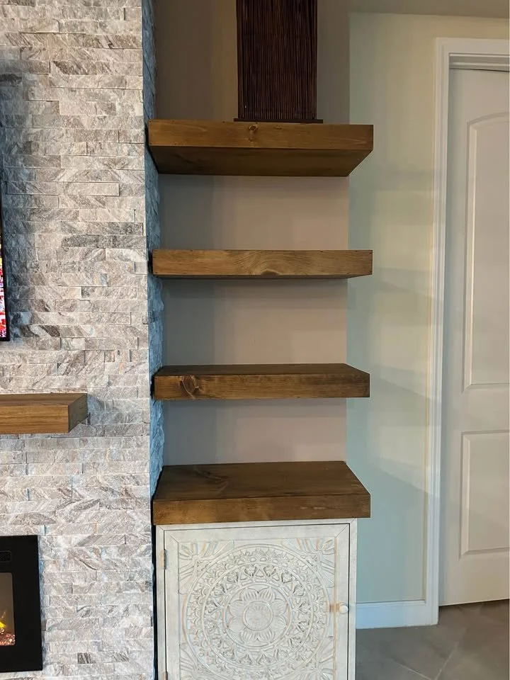 floating wood shelves and storage cabinet next to ledger stone fireplace media wall with custom wood mantel