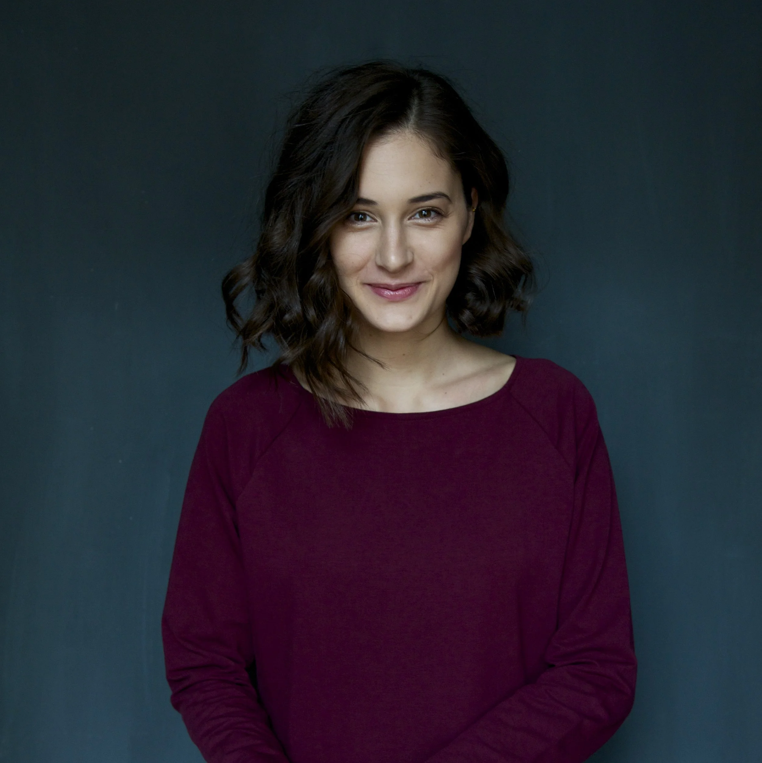 A landscape with a tranquil lake surrounded by green hills and distant mountains under a cloudy sky.