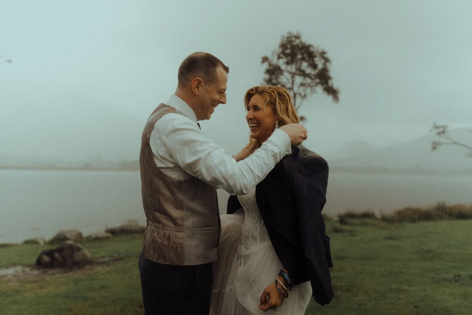 kilchurn elopement photo bride and groom laughing sharing jacket