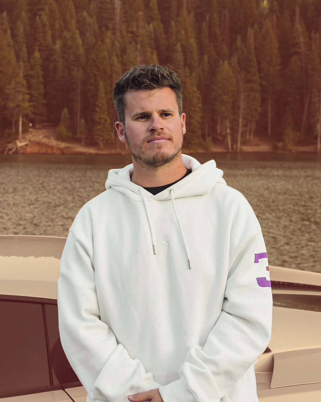 Founder of B Social Sitting on a car by the lake