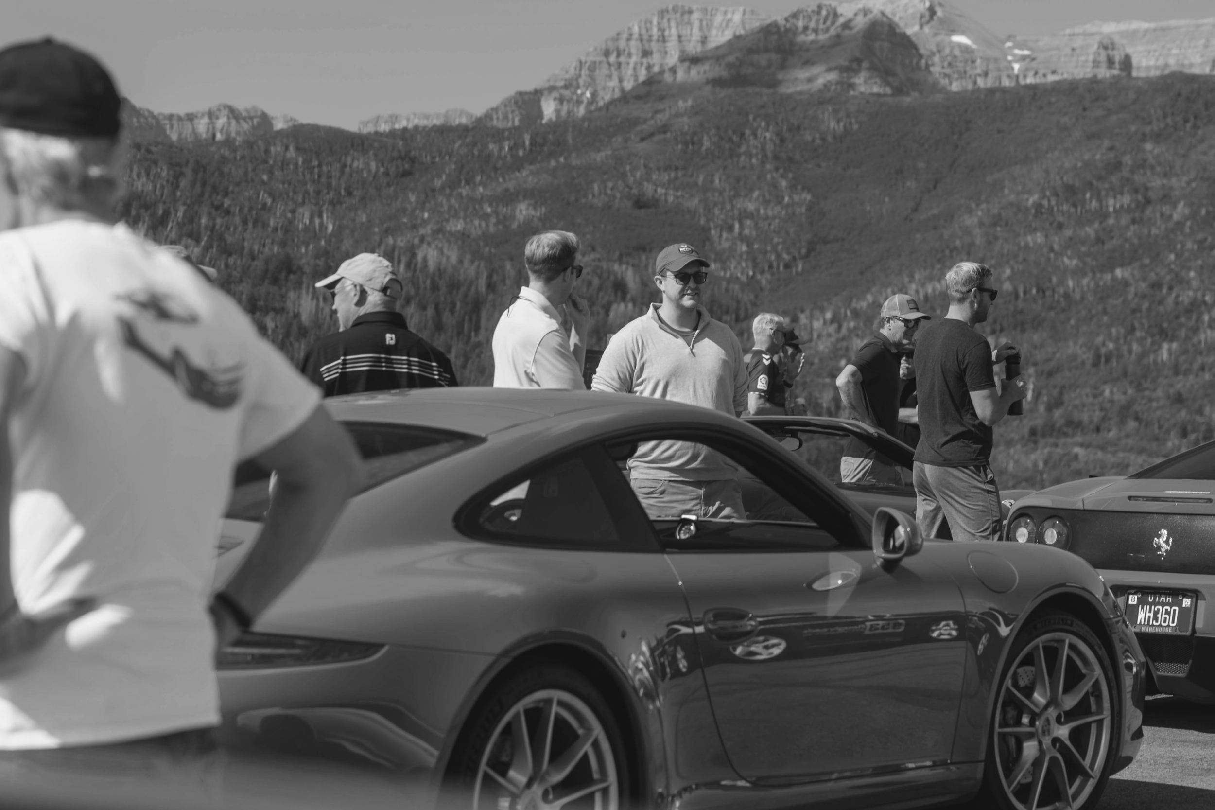 A group of people standing in a parking lot, with mountains in the background.