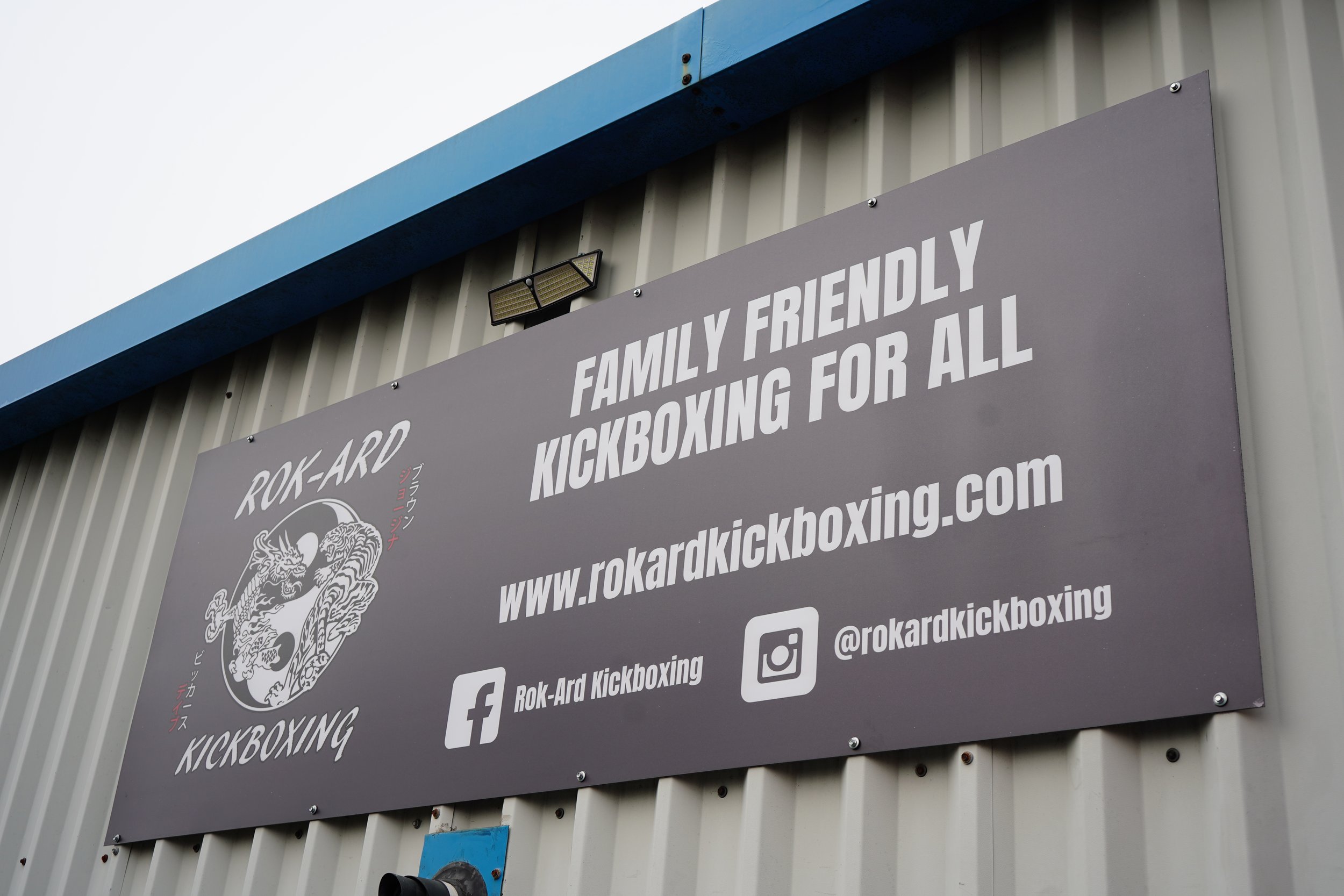 Outdoor sign promoting Rok-Ard Kickboxing, family friendly, comes with website, Facebook, and Instagram details.