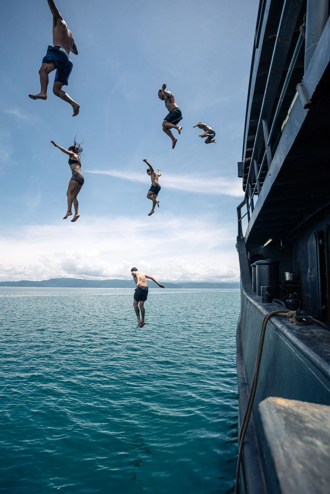 COnservation volunteers jumping off a boat - the conservation vessel Modoc - into the water on a sunny day.