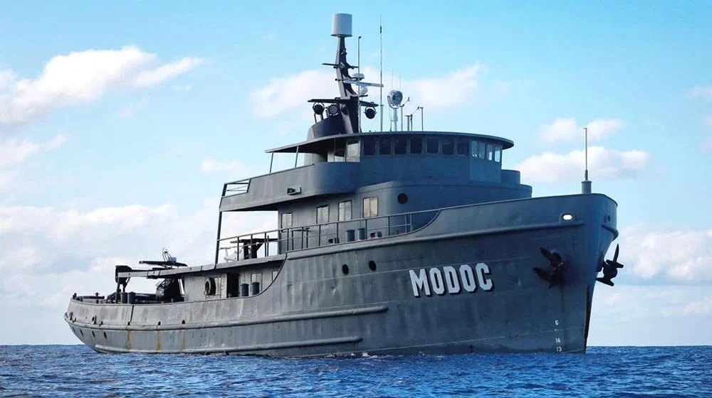 Grey ship, former navy vessel called Modoc, now conservation vessel in costa rica 