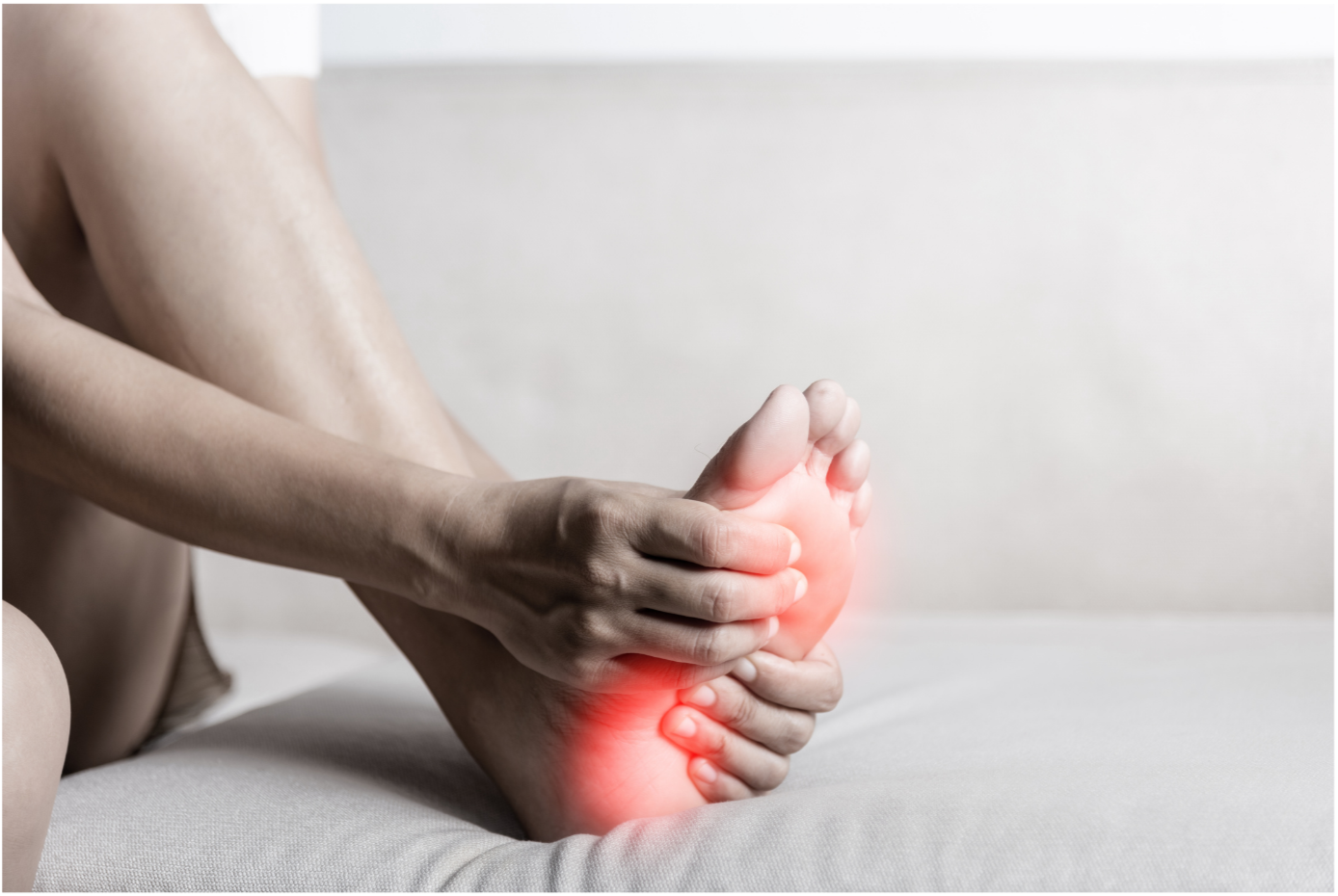A patient holding their left foot with their right hand. A red highlight indicates pain along the bottom of their foot. The text attached to the image says "Plantar Fasciitis"