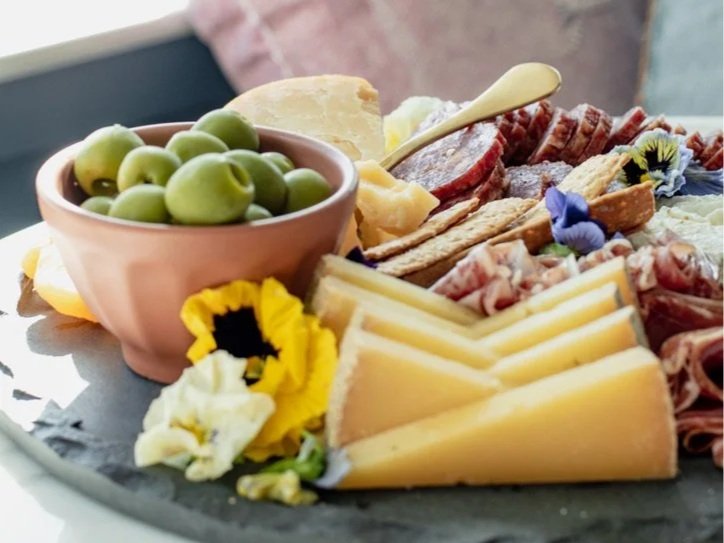 Charcuterie board with cheese, meats, grapes, and edible flowers