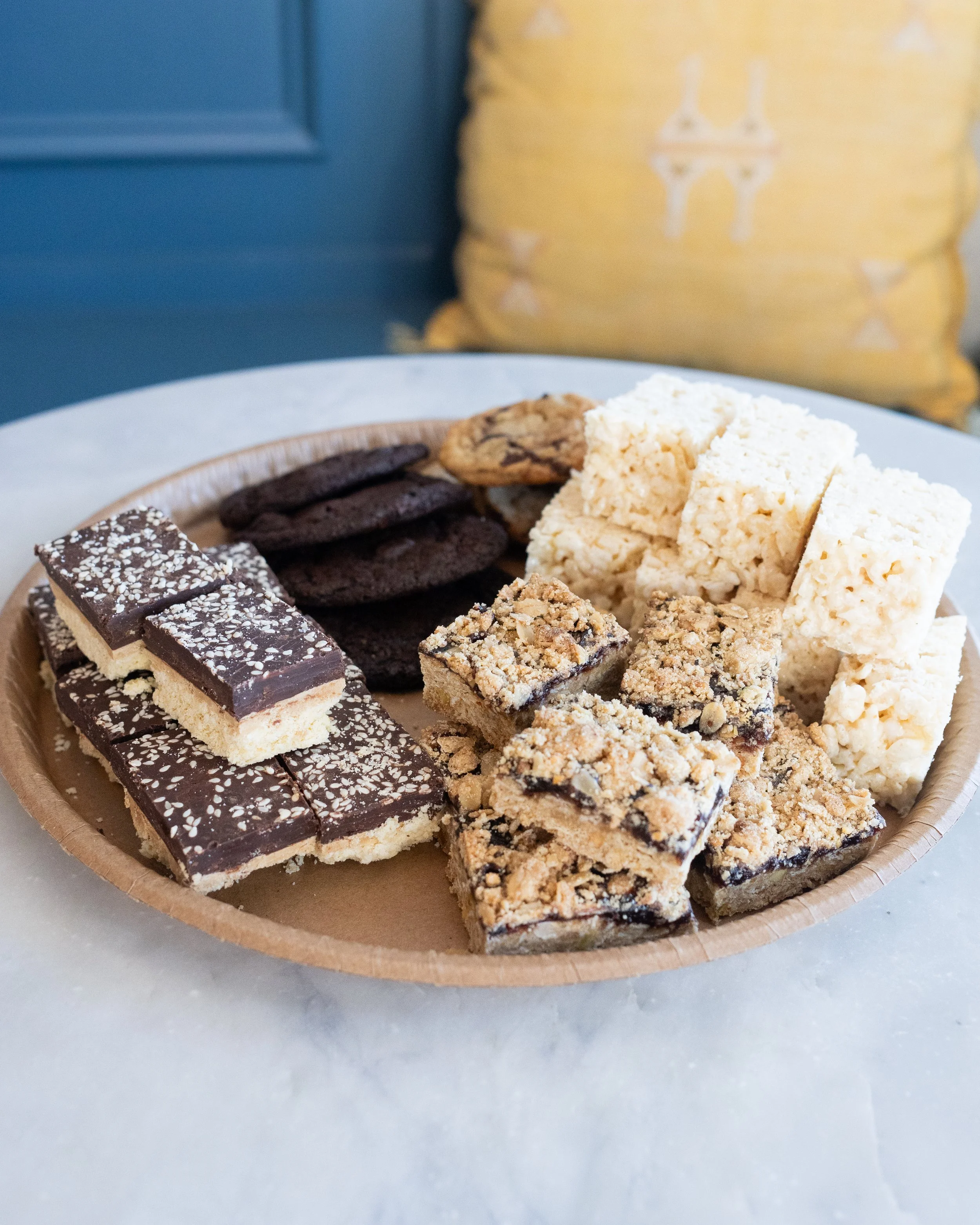 Assorted cookies and rice krispie treats on a round paper tray