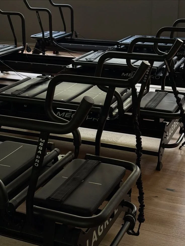 Multiple black Pilates reformer machines arranged in a fitness studio.