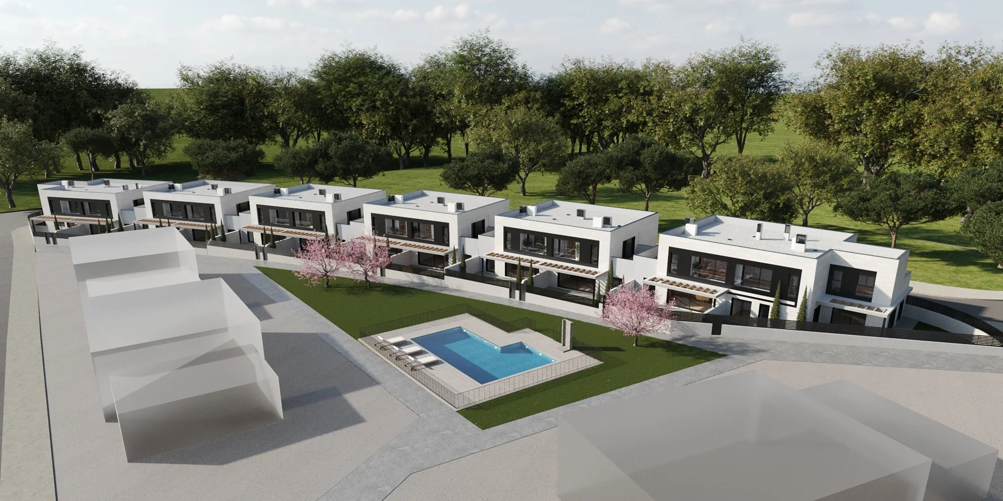 A modern residential complex with multiple white houses featuring large windows, balconies, and sloped roofs, surrounding a central outdoor swimming pool with lounge chairs and pink flowering trees, set against a backdrop of green trees and grass.