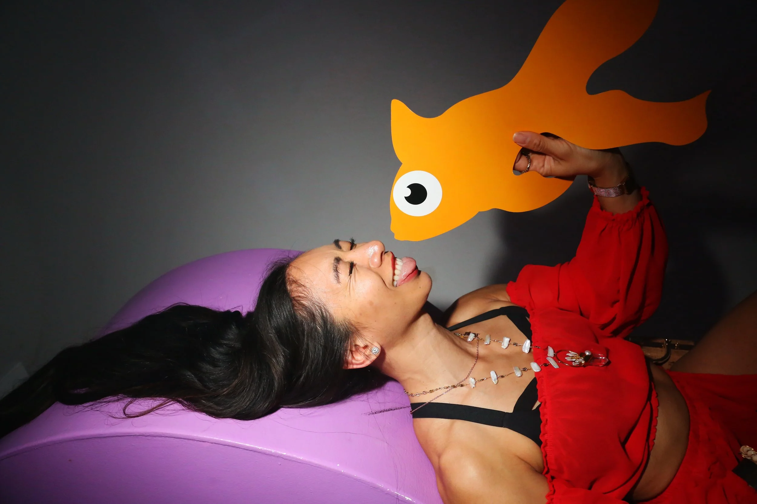 Participant reclines beneath a playful sculptural character during an immersive art experience.