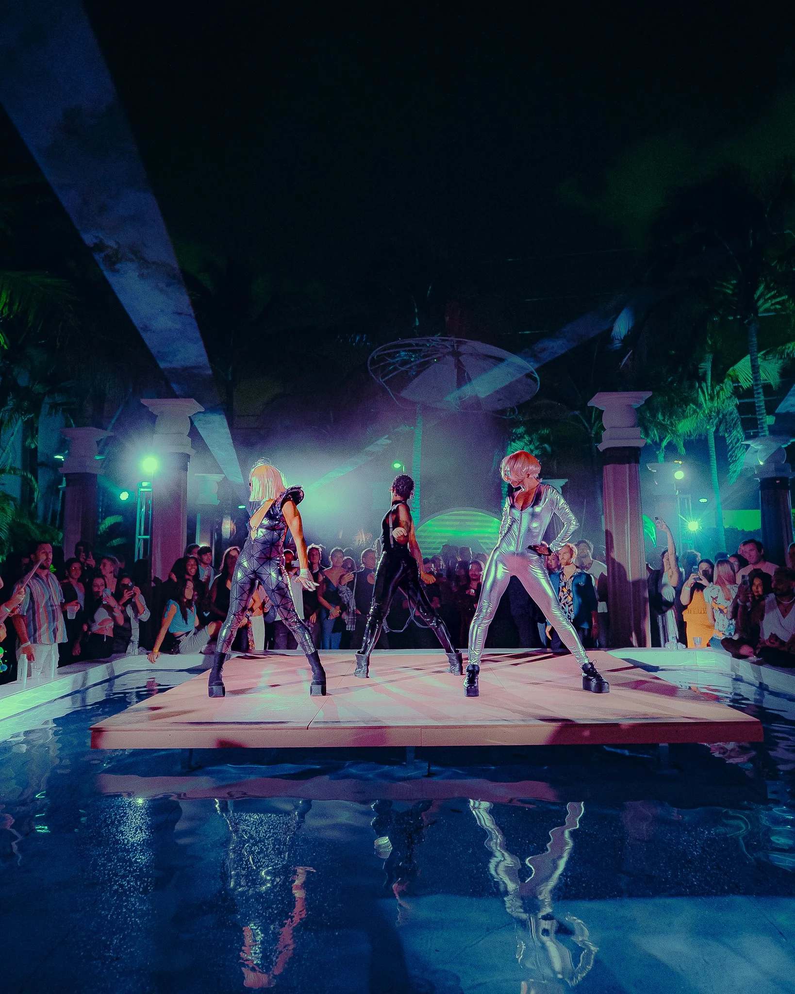 Performers on an illuminated stage surrounded by guests at Teleport City during Miami Art Week.