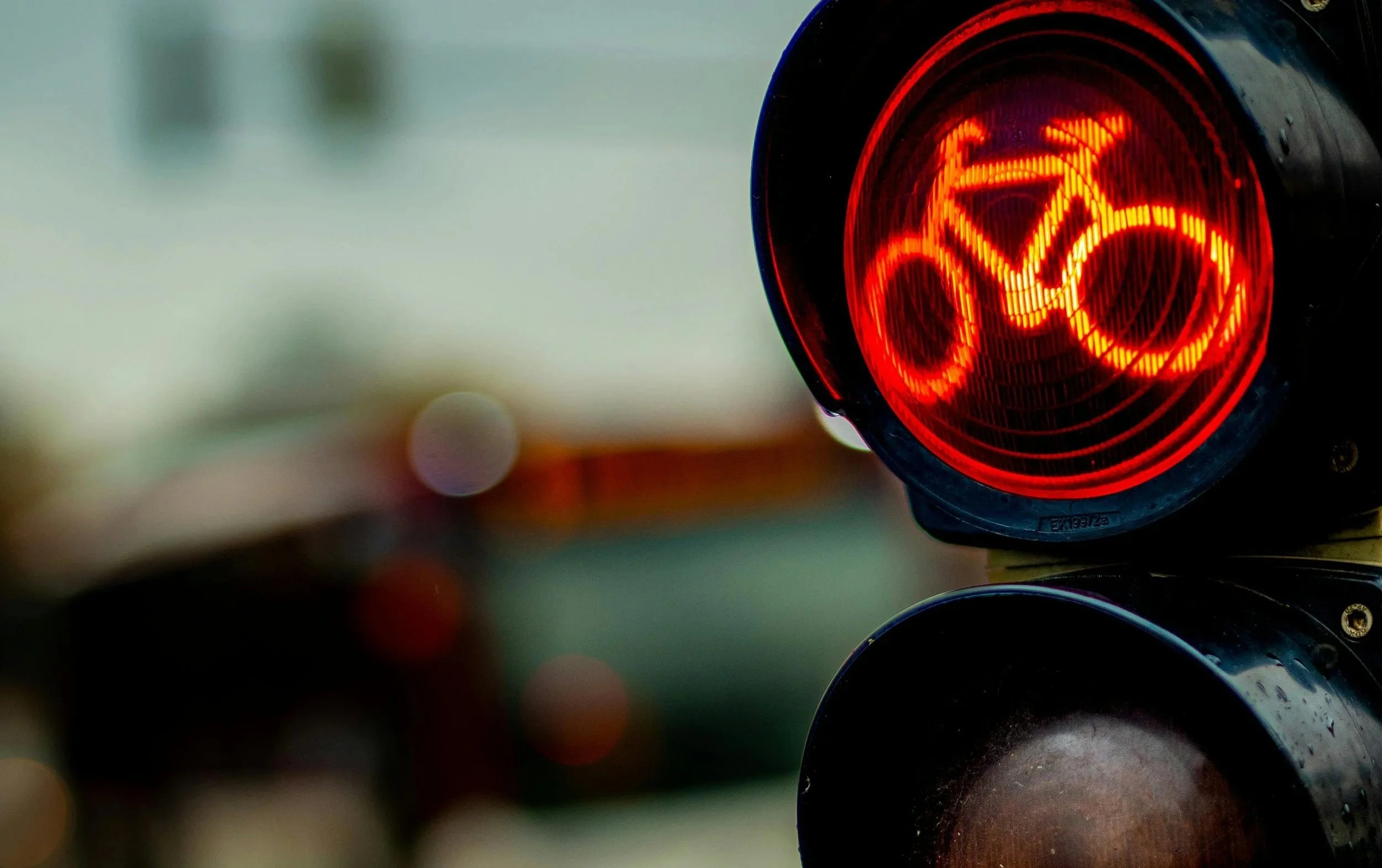 Close-up of a red traffic light with an arrow, reflecting on a shiny black surface.