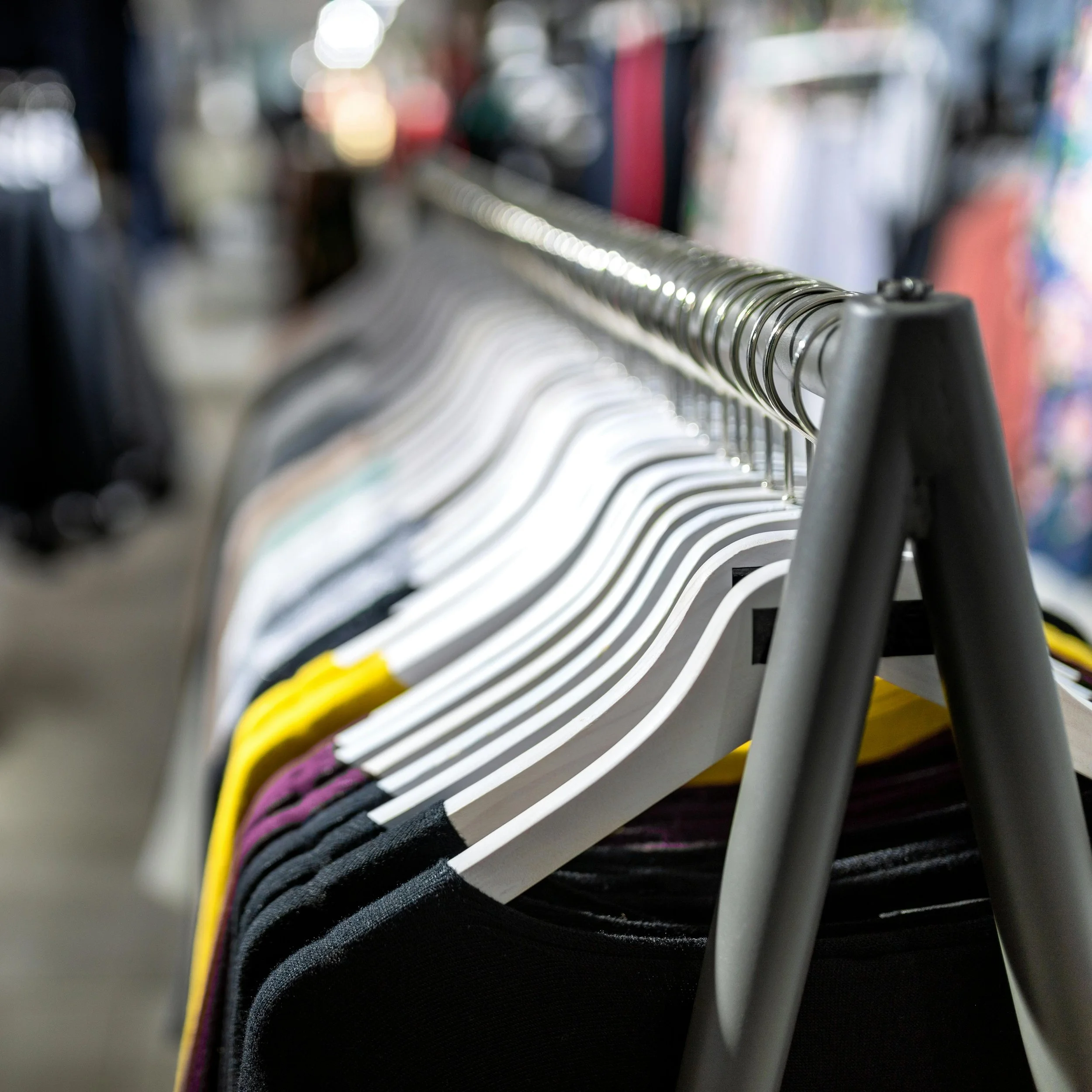 Close-up of a rack of multicolored hangers, with out-of-focus clothing or fabric in the background.