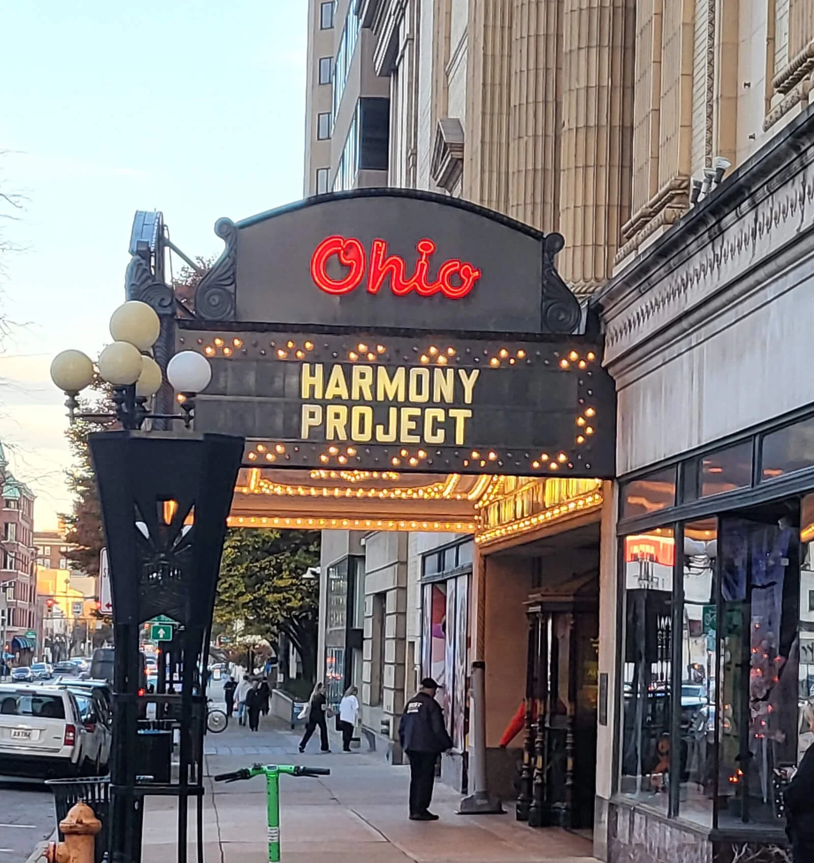 The Ohio Theatre marquee advertising Harmony Project, with city street and pedestrians visible.