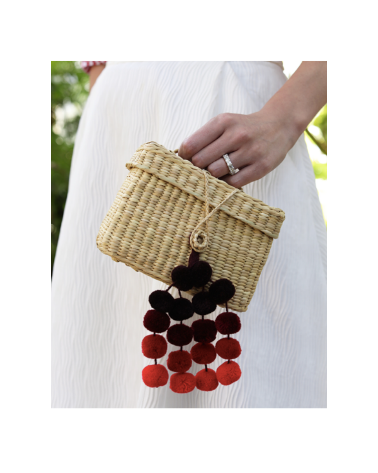 women's hand holding a mini wicker Nannacay with a pompom pendant