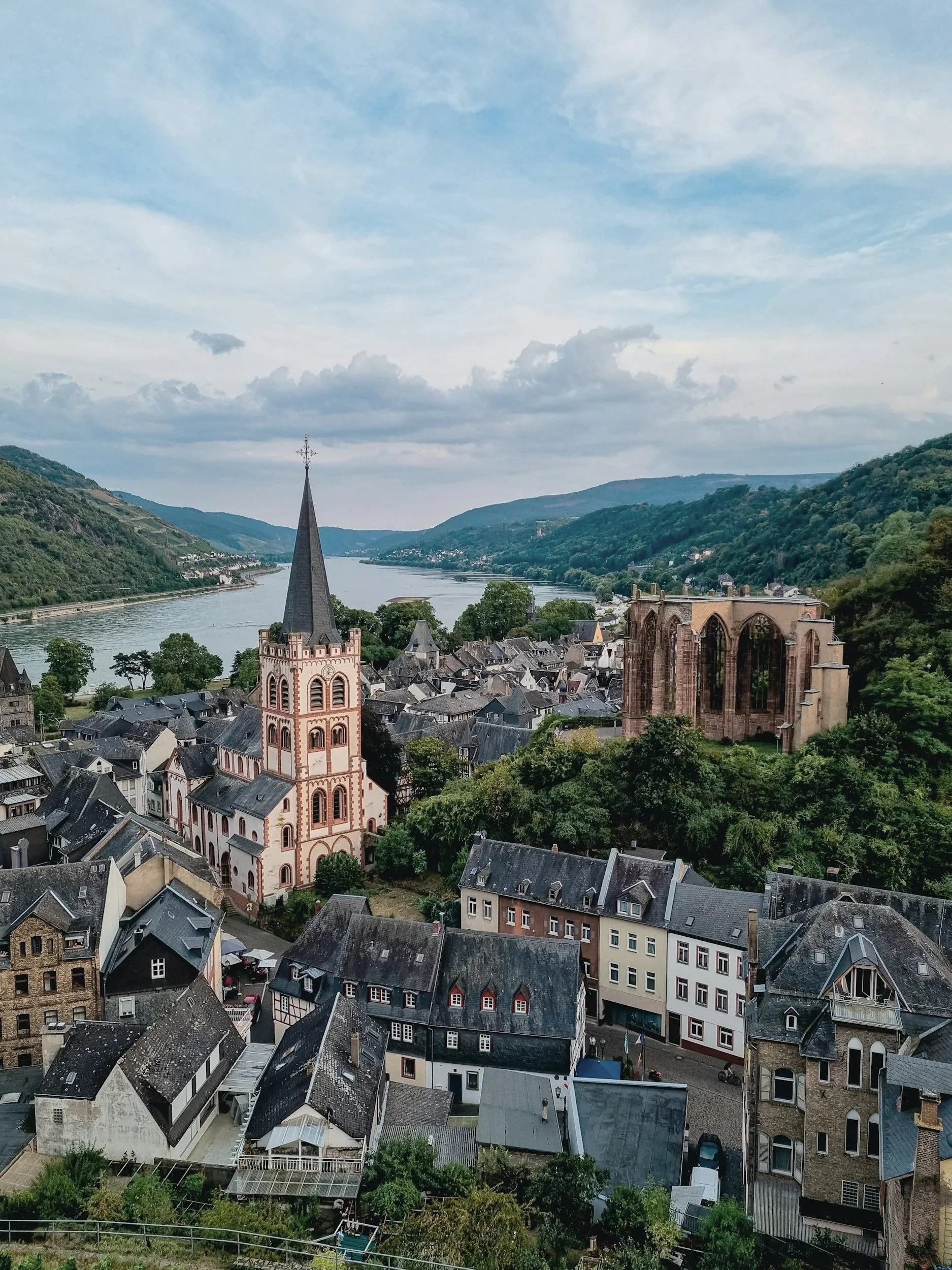A town by a river with a church, ruins, and hillside homes.