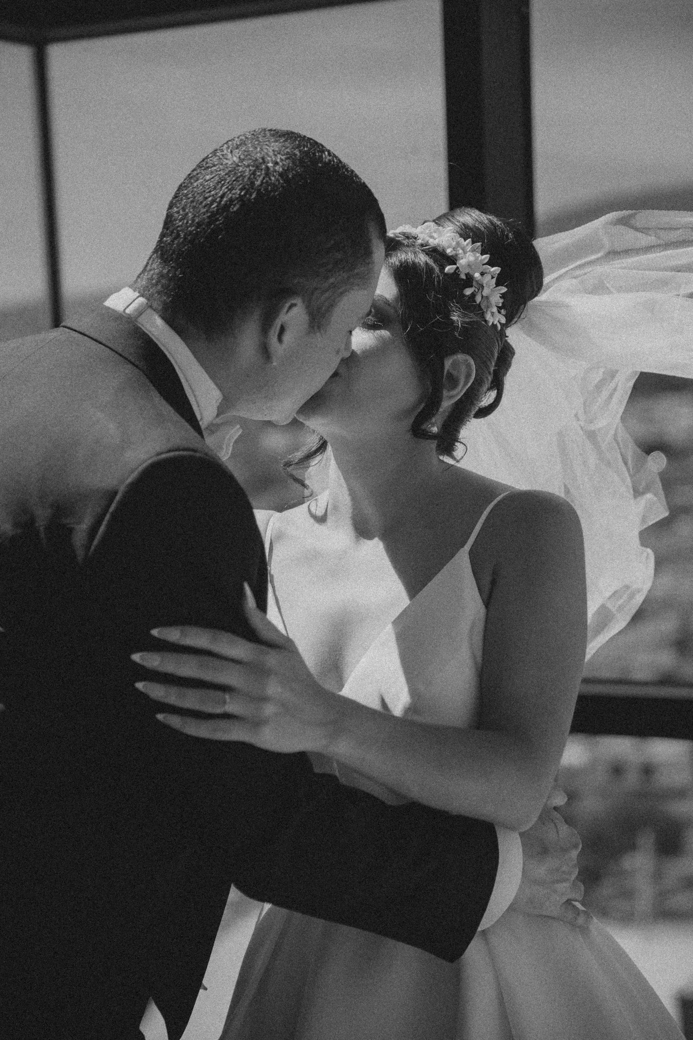 Una pareja en su boda se besa en un ambiente íntimo y romántico.