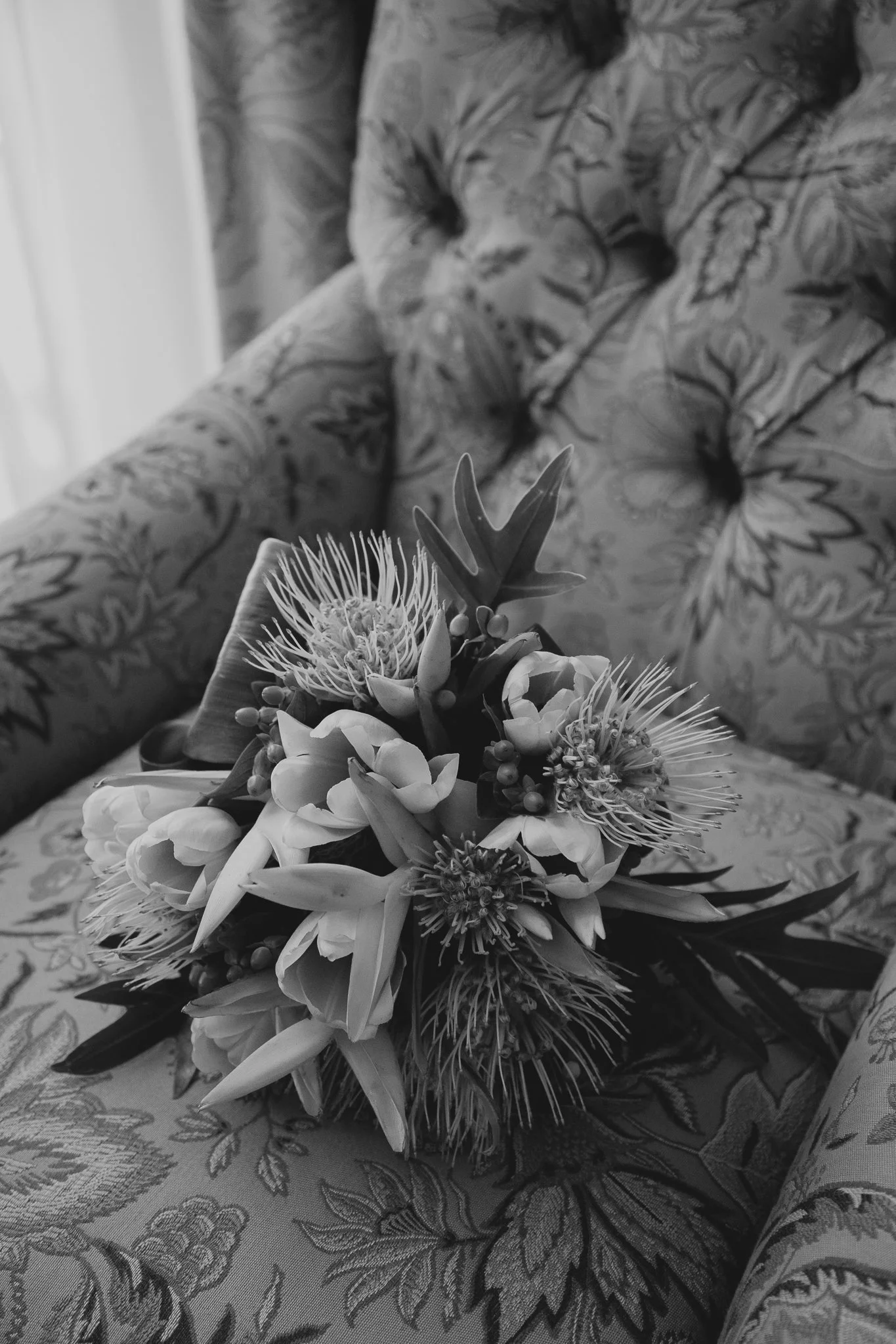 Ramo de flores sobre un sillón tapizado con un patrón floral.