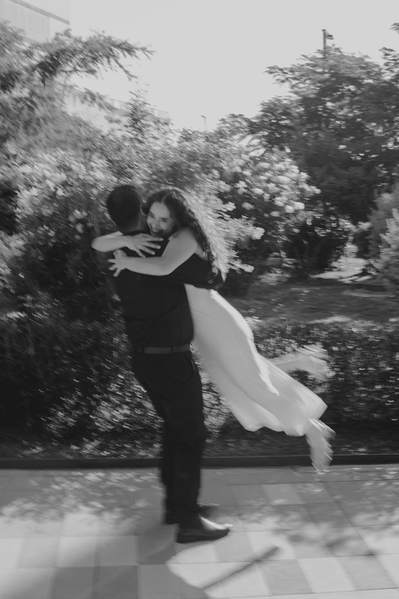 Dos personas bailando románticamente al aire libre, con árboles y follaje de fondo a la luz del atardecer.