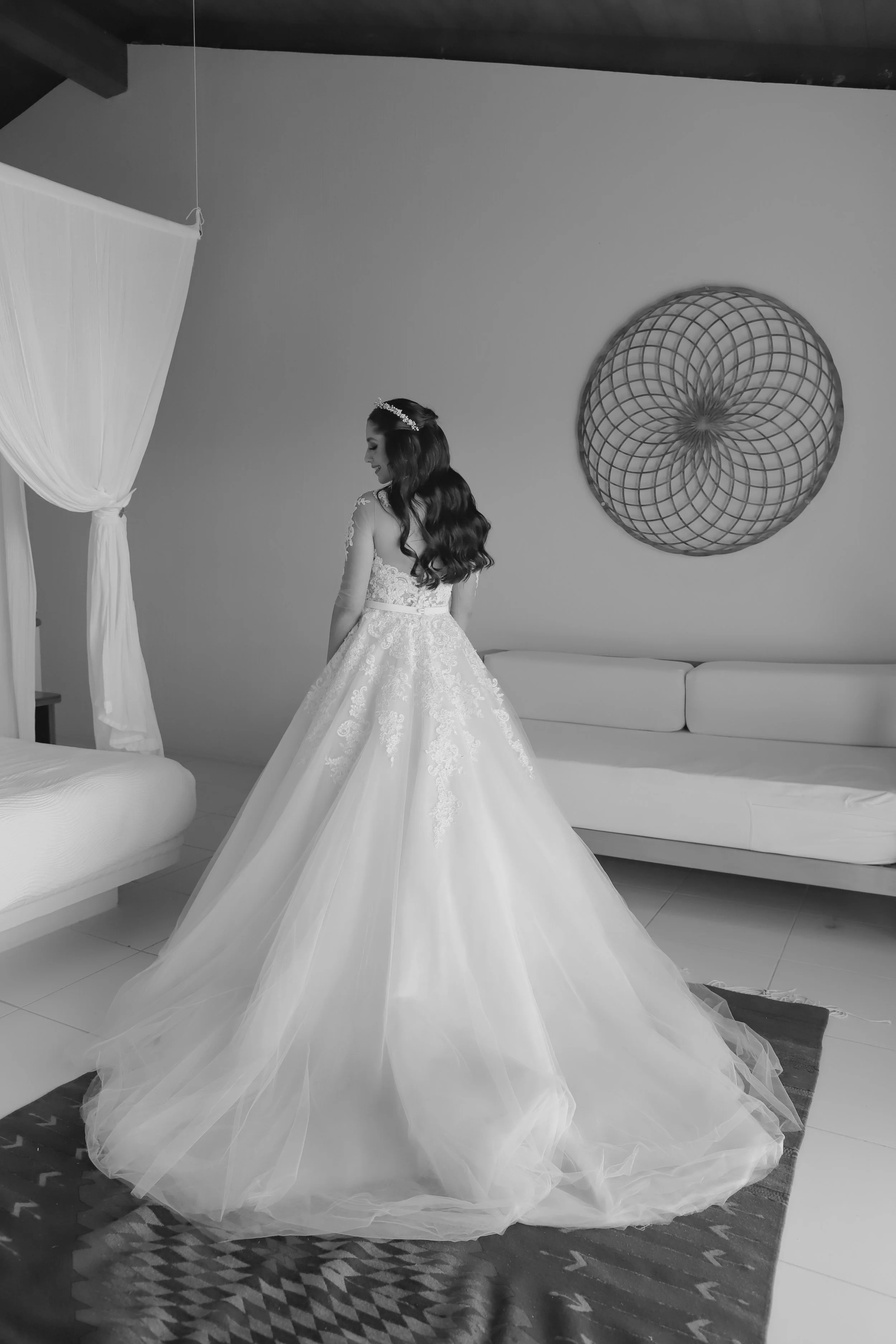 Mujer con vestido de novia de espaldas en una sala decorada, en tonos grises y blancos.