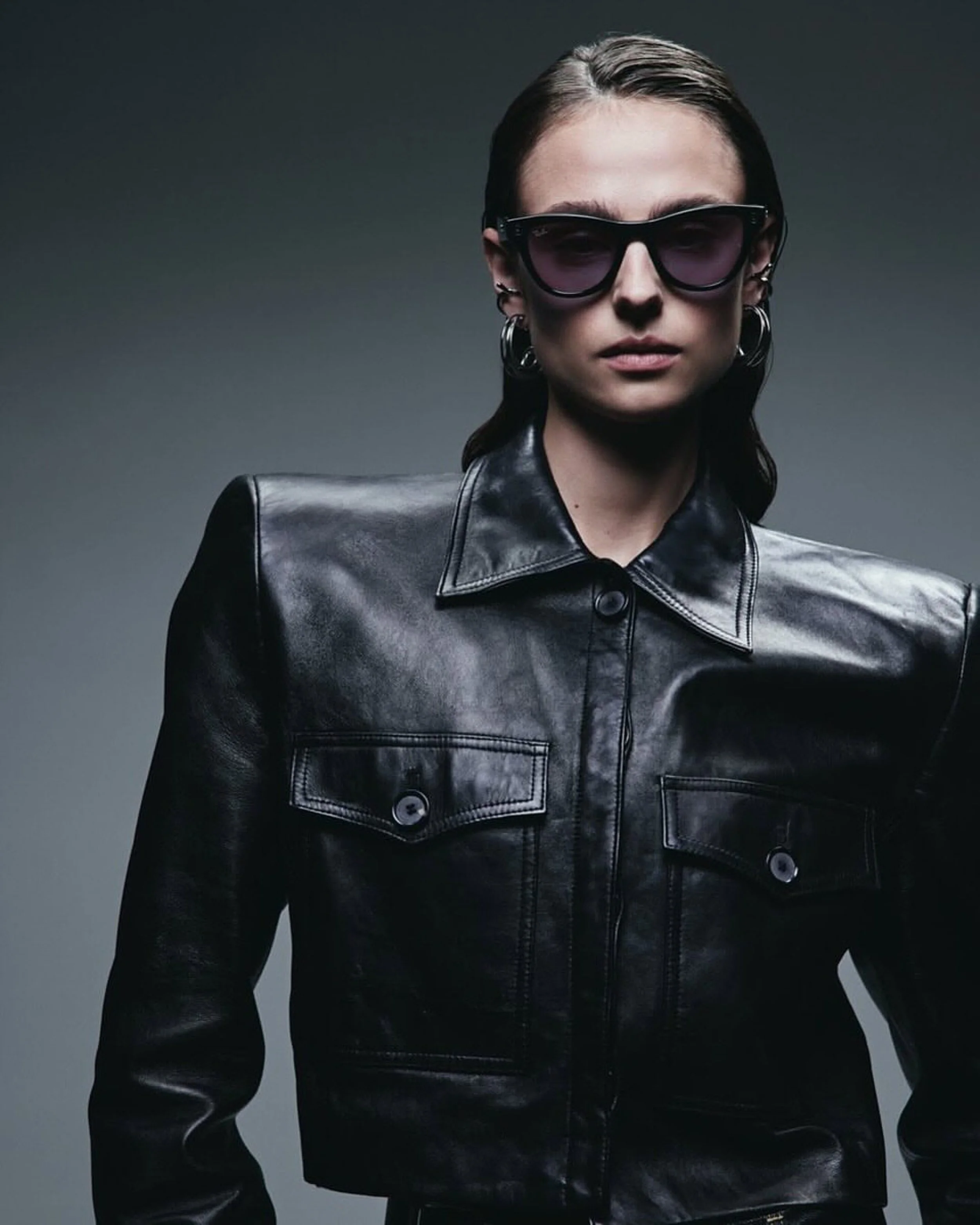 A woman wearing large black sunglasses and a black leather jacket.