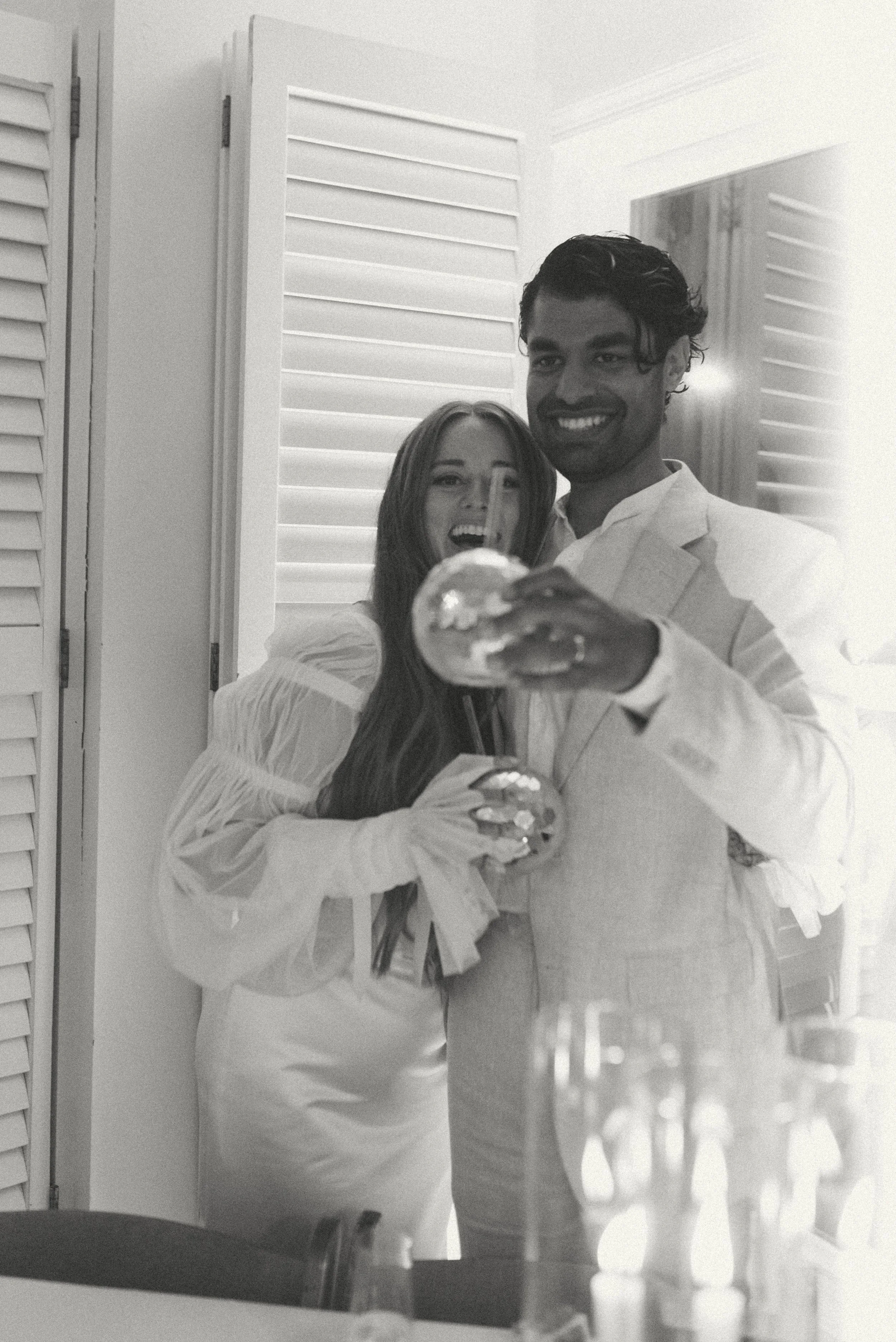 Bride and groom celebrating with drinks, smiling at their guests at the reception.  