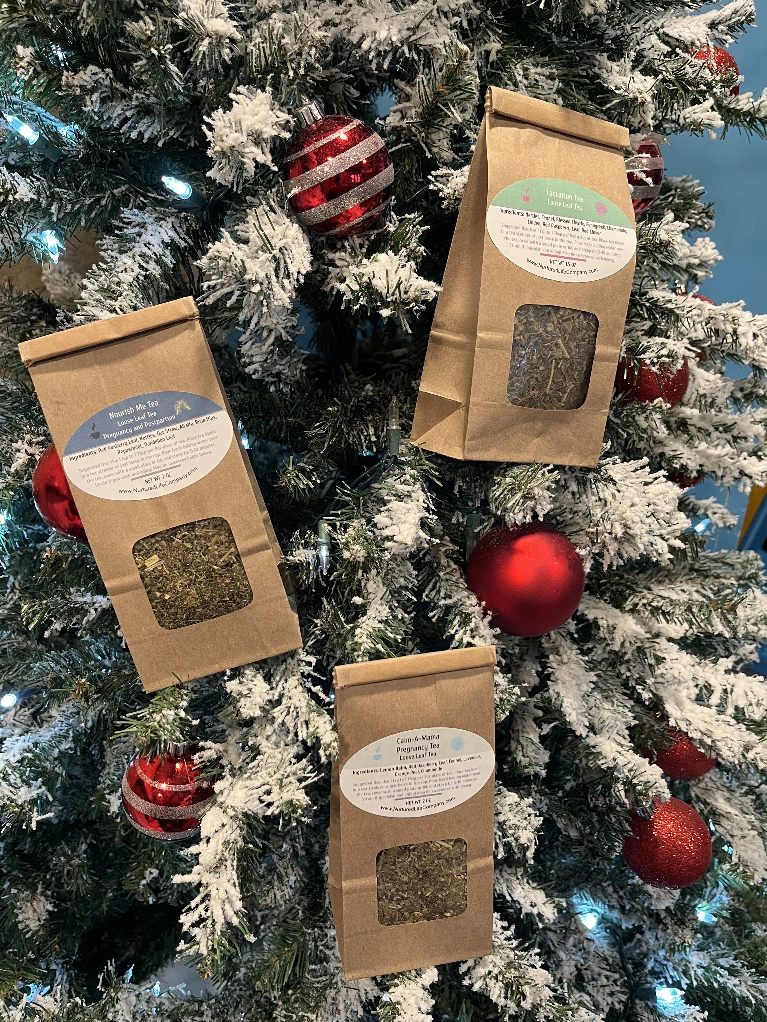 Three eco-friendly herbal tea pouches arranged in the shape of a Christmas tree on a cozy holiday background — perfect pregnancy, postpartum, and nursing gifts for expecting or new moms.