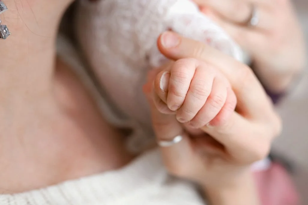 Close-up of a person's hand holding a baby's hand.