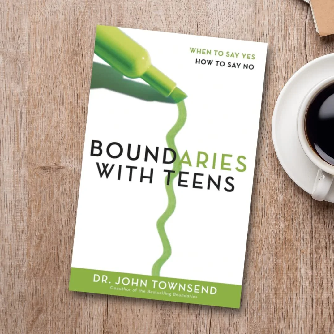 Book titled 'Boundaries with Teens' by Dr. John Townsend, placed on a wooden table next to a cup of coffee.