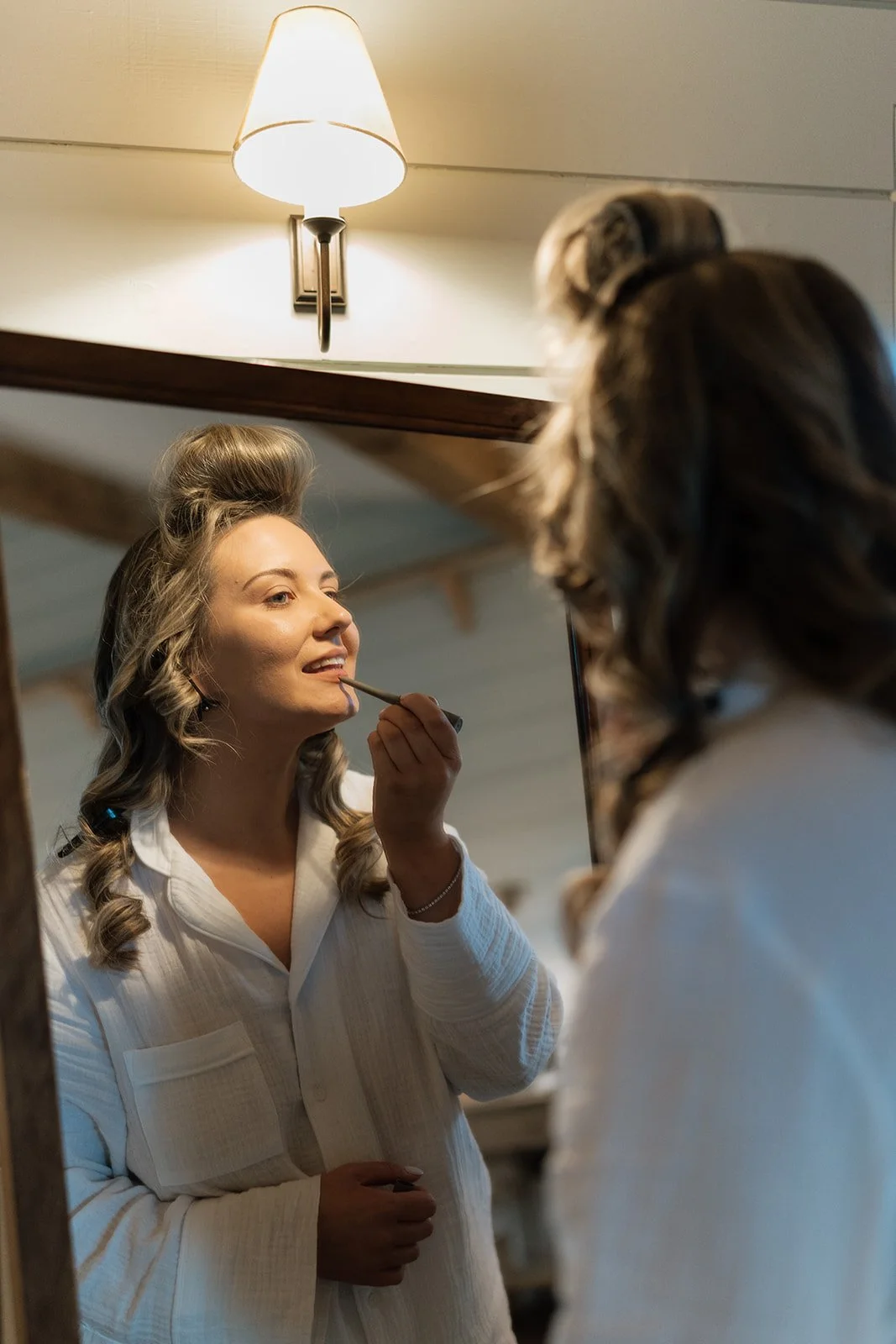 Woman applying makeup while looking in a mirror