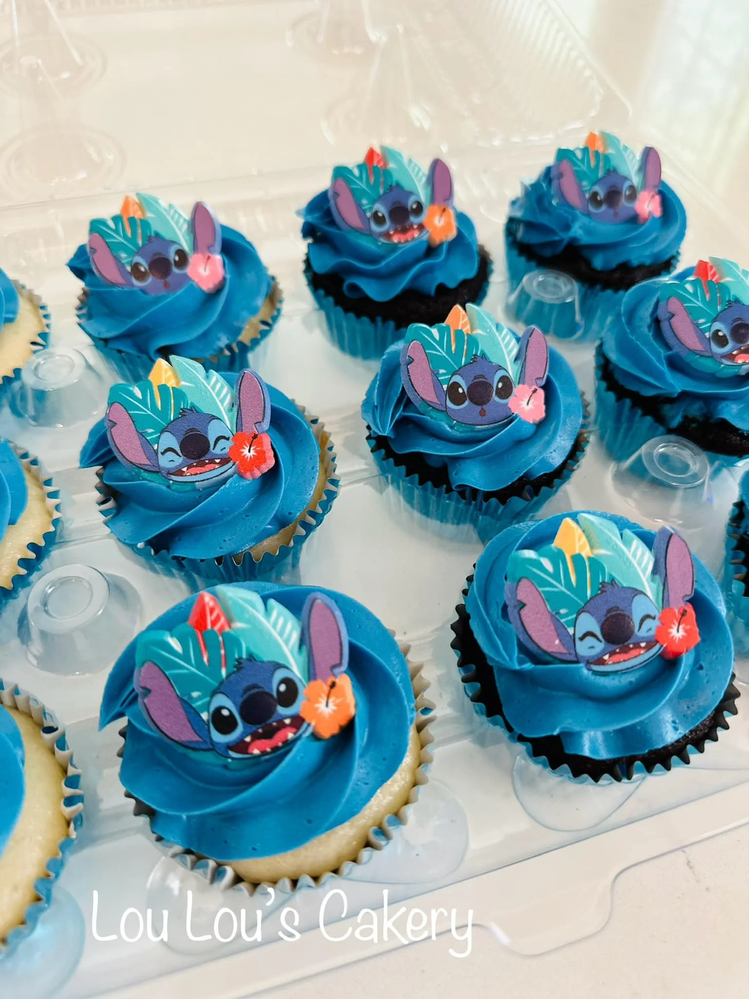 Cupcakes decorated with blue frosting and edible toppers featuring Stitch from Disney's "Lilo & Stitch" holding a pink flower.