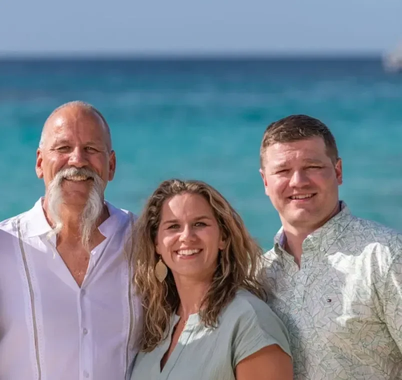 Hickory Creek Builders - Builders At Crane Island. Three people smiling on a beach with the ocean in the background.