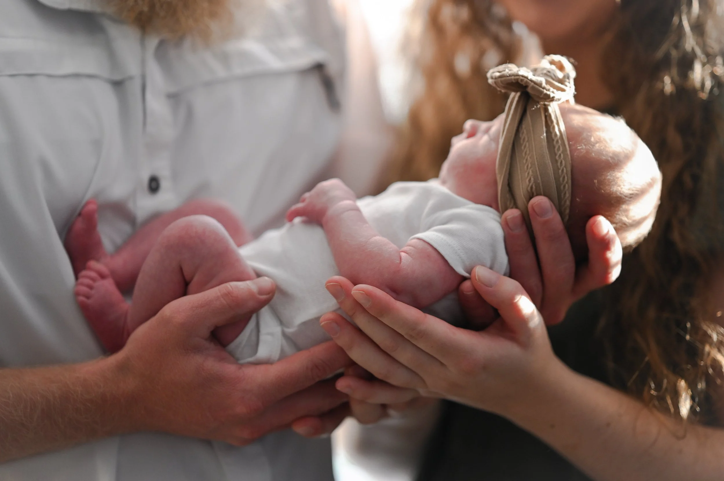 A newborn baby being cradled in two people's hands.