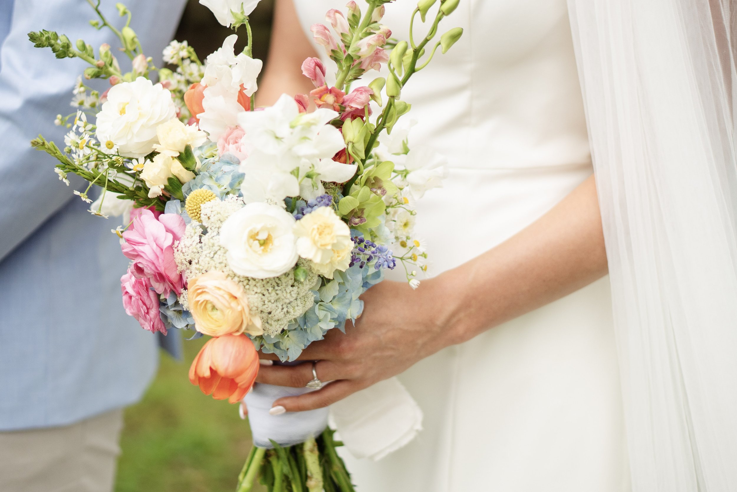 A bride and groom holding a colorful bouquet of flowers at a wedding.