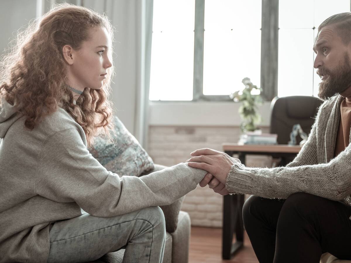 Couple talking on a couch, one partner appearing tense during a discussion about relationship needs