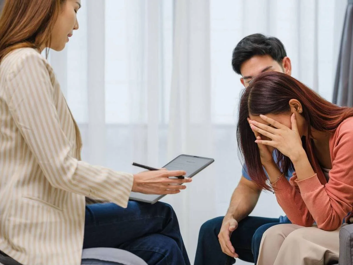 Person sitting with hands on their face, appearing overwhelmed during couples therapy
