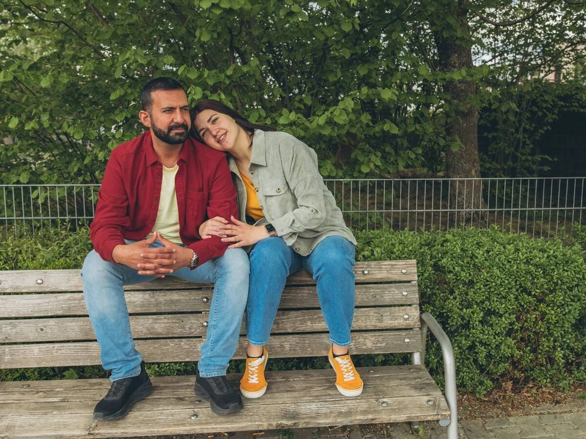 Couple reconnecting on a bench after taking space, sitting close again with gentler body language.