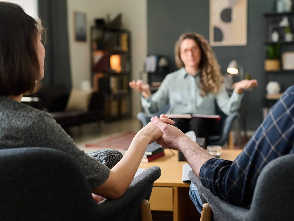 Couple sitting together in therapy after conflict, beginning to reconnect