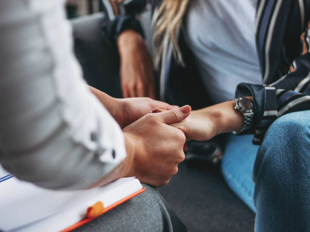 Close-up of partners holding hands during a vulnerable moment, symbolizing repair, emotional safety, and reconnection in couples therapy.