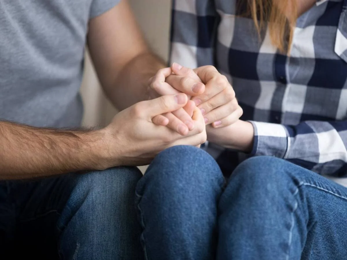 Close-up of two partners holding hands, symbolizing repair and emotional reassurance after conflict