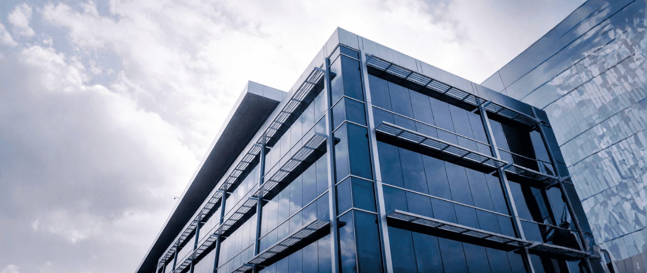 Cinematic upward-angle view of a modern glass commercial office building exterior in New York City under neutral daylight