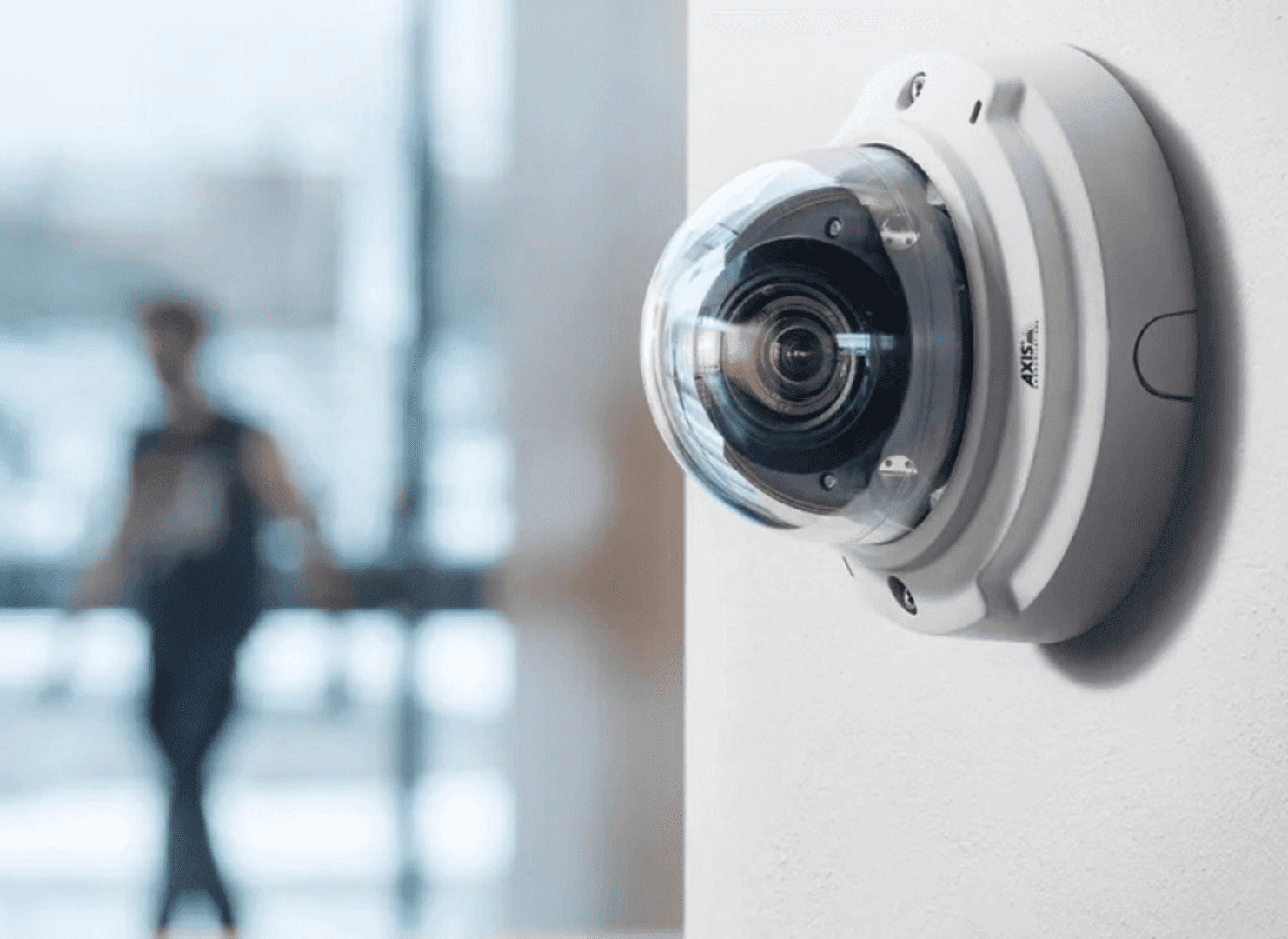 Axis dome security camera installed on a wall monitoring activity inside a commercial building.