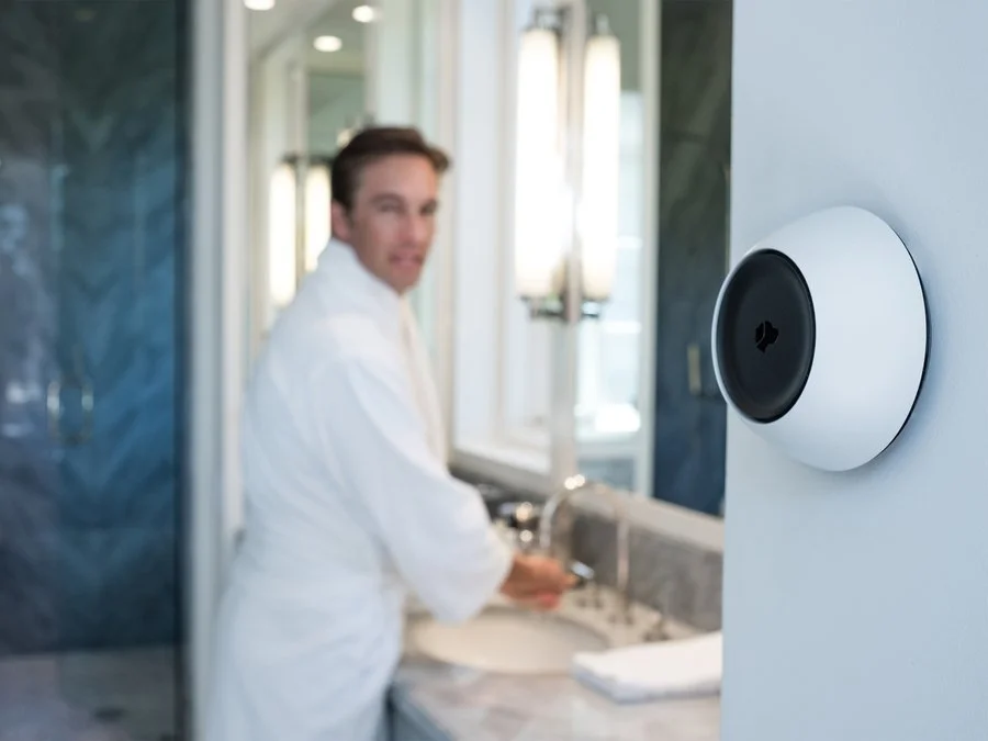Wall-mounted Josh Micro in a bathroom, with a person at the vanity in the background.